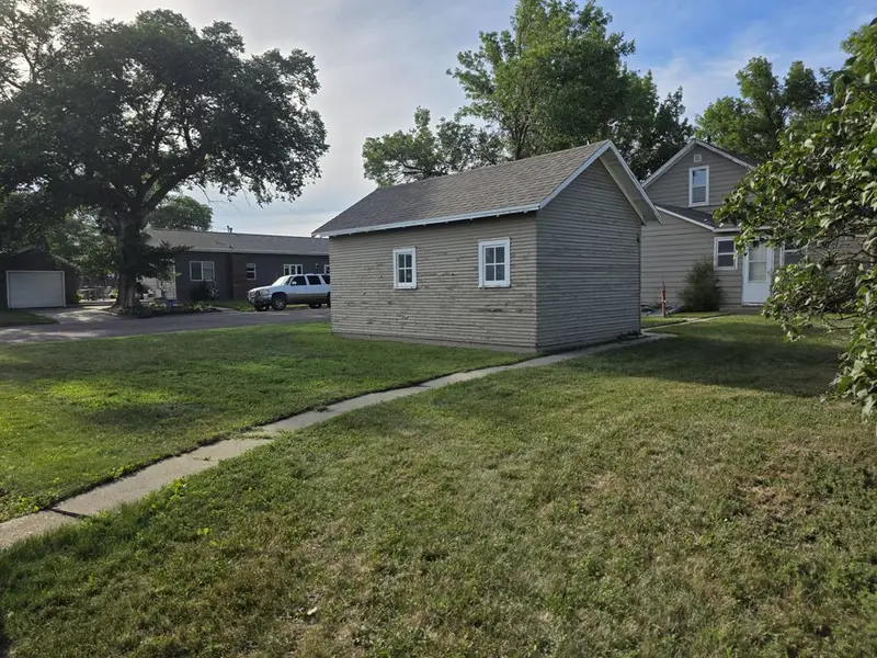 A mown backyard with a path leading to a garage