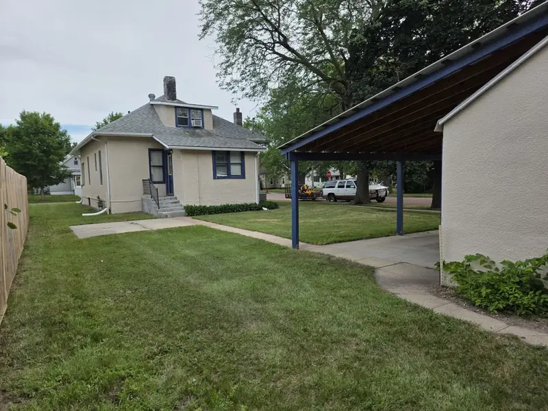 A mown side yard between a house and a carport