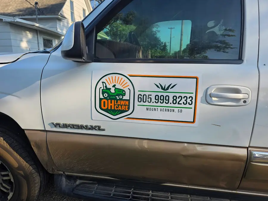 Close-up of the OH Lawn Care badge and phone number on the truck door