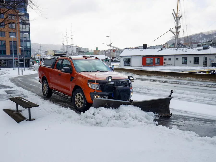 A pickup truck with a plow blade pushing snow off a parking area