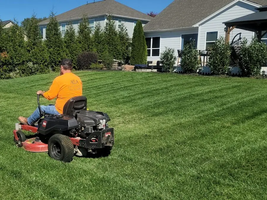 A zero-turn mower laying stripes across a residential backyard